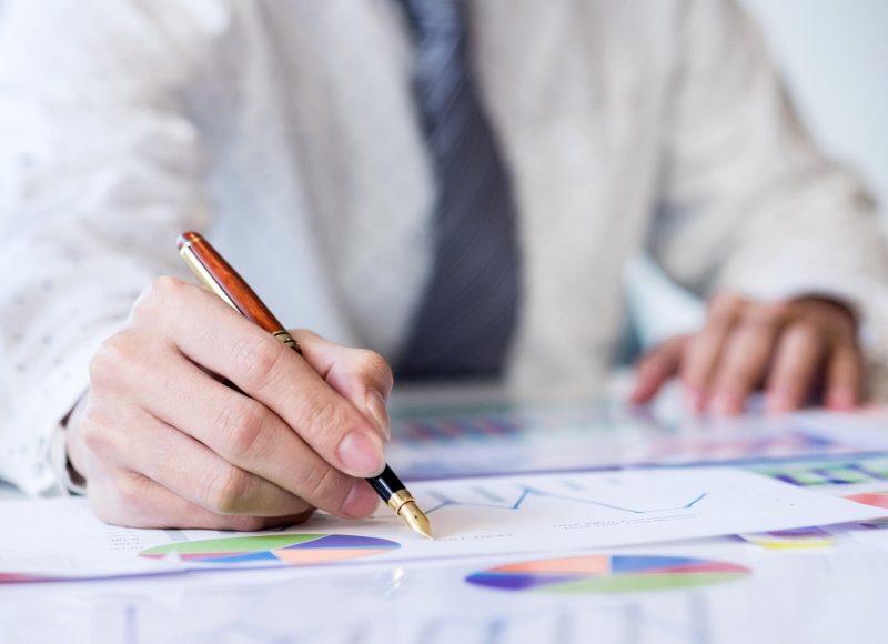 Working process startup. Businessman working at the wood table with new finance project. Modern notebook on table. Pen holding hand